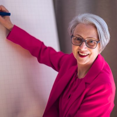 Susanna Schulz erklärt am Whiteboard – 30 Jahre Praxis in internationaler Zusammenarbeit